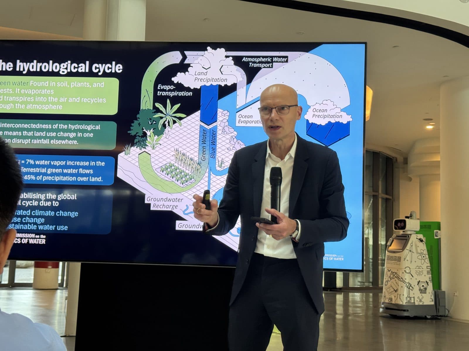 A speaker presenting a diagram of the hydrological cycle during the symposium
