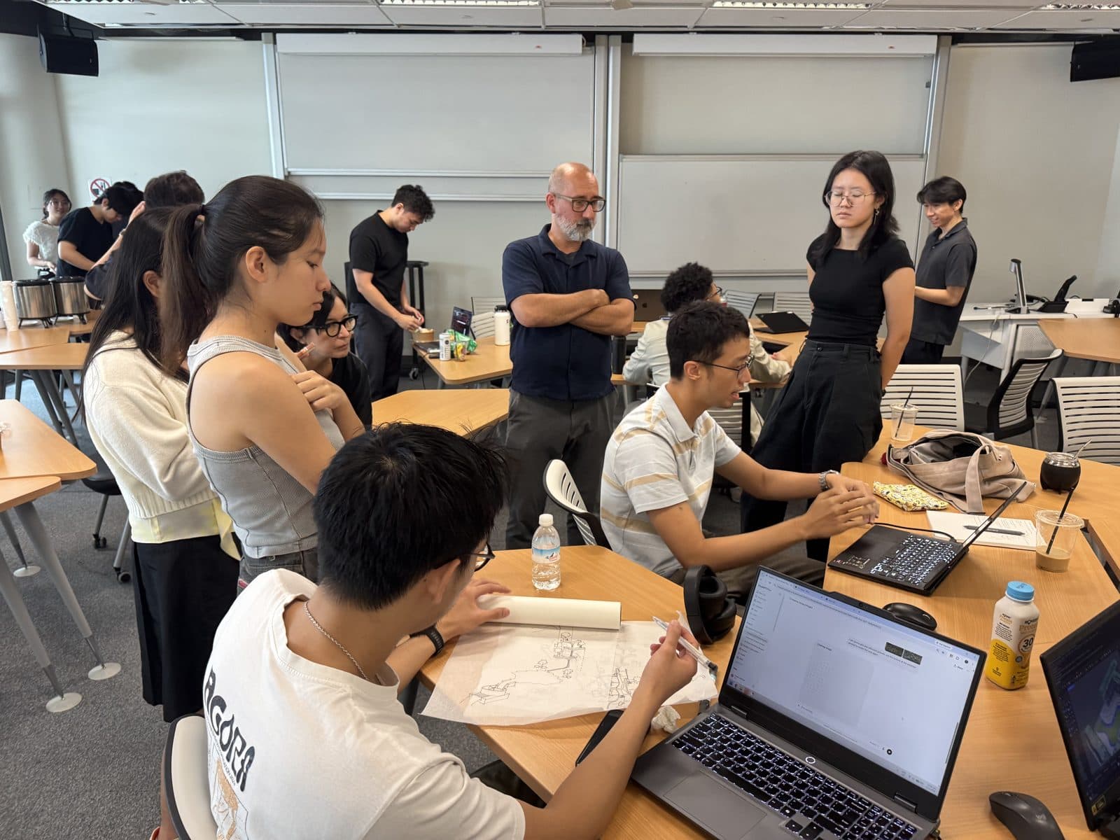 Workshop participants working in groups at laptops and drawings